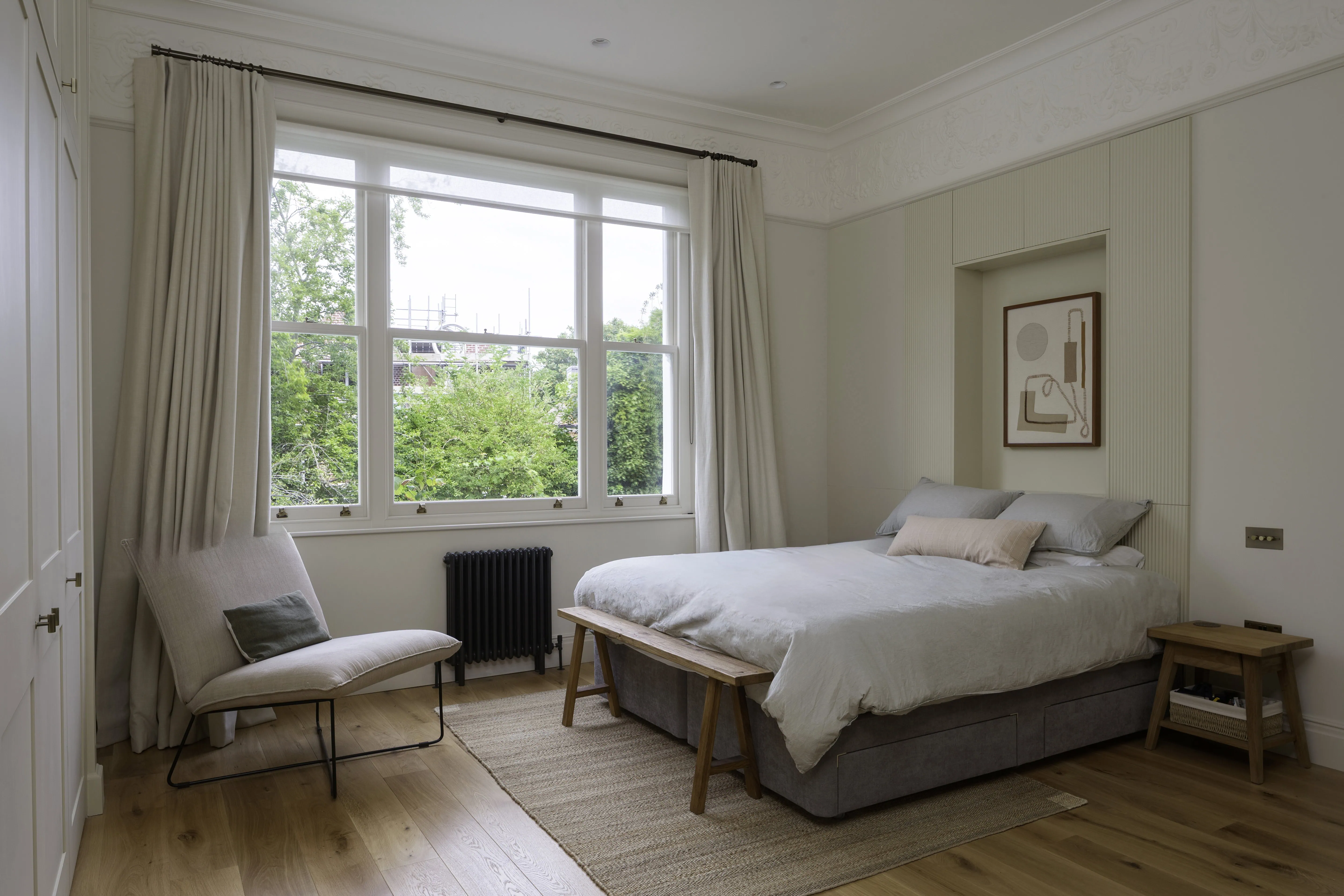 Principal bedroom with soft textiles and period detailing in a Belsize Park flat