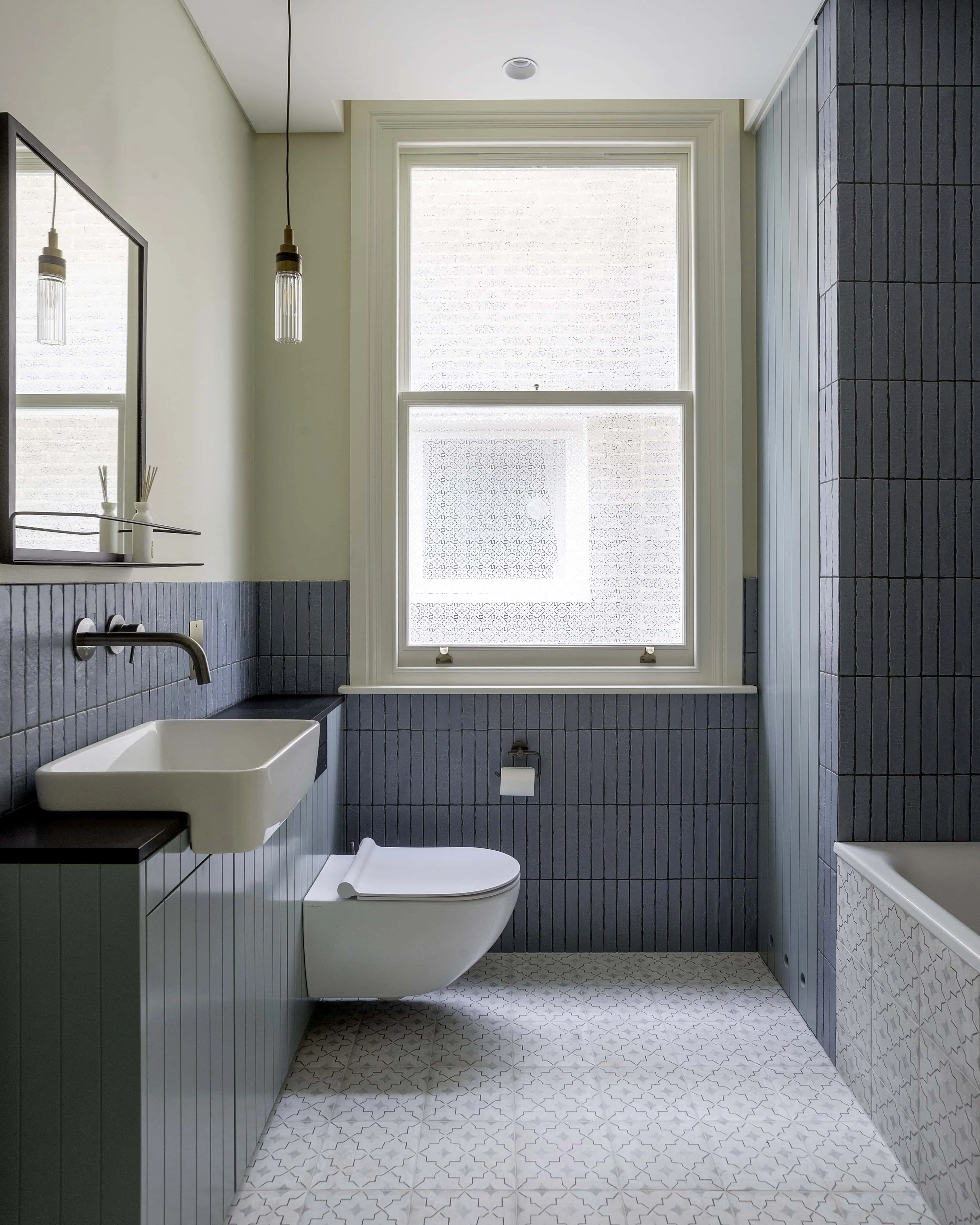 Family bathroom with modern tiles, window, and brushed black fittings in Belsize Park flat