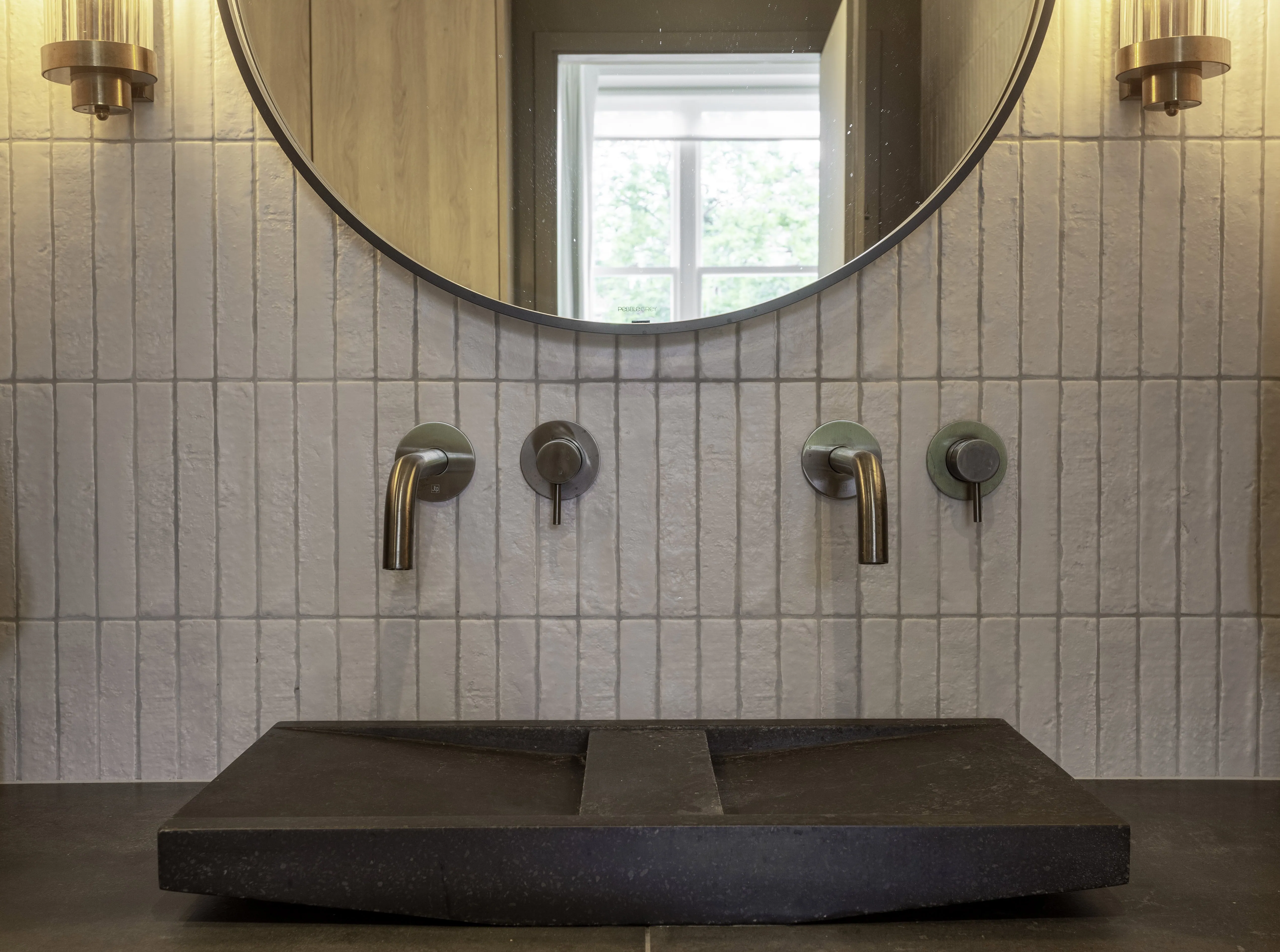 Principal bedroom vanity with round mirror and modern lighting in Belsize Park flat