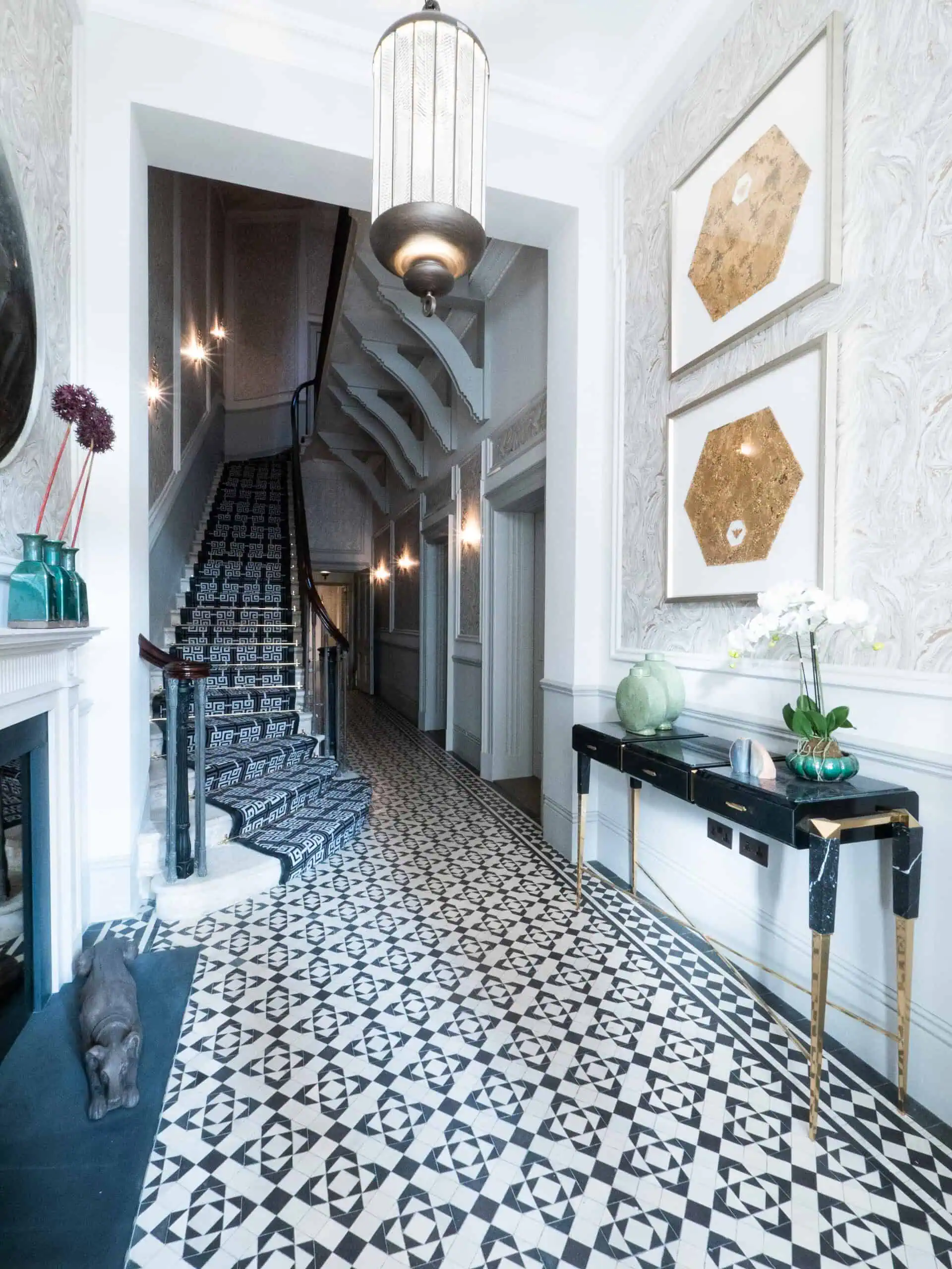 Grand entryway with patterned tile flooring, statement lighting, and staircase.