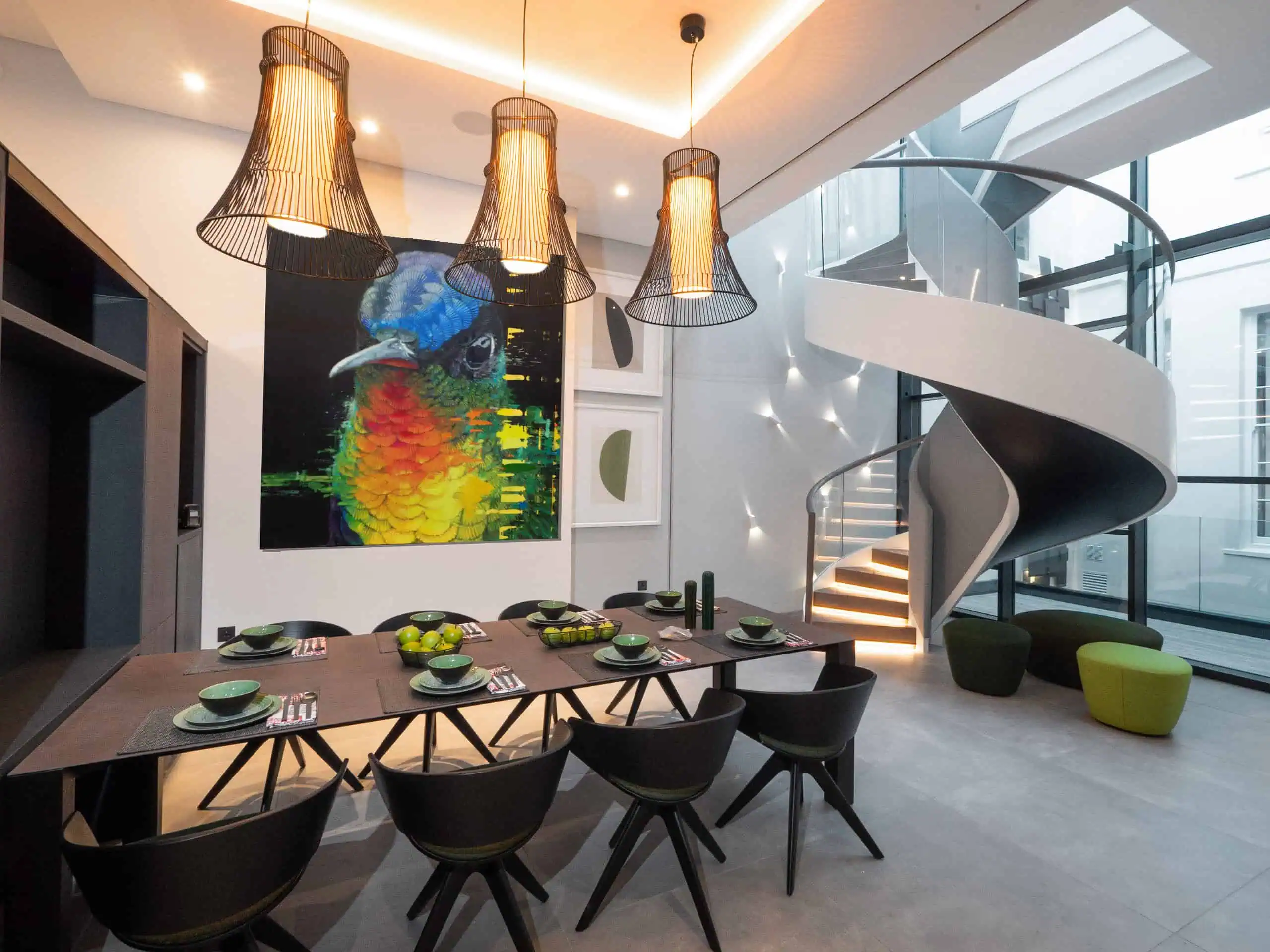 Dramatic dining room with spiral staircase, bold artwork, and designer lighting.