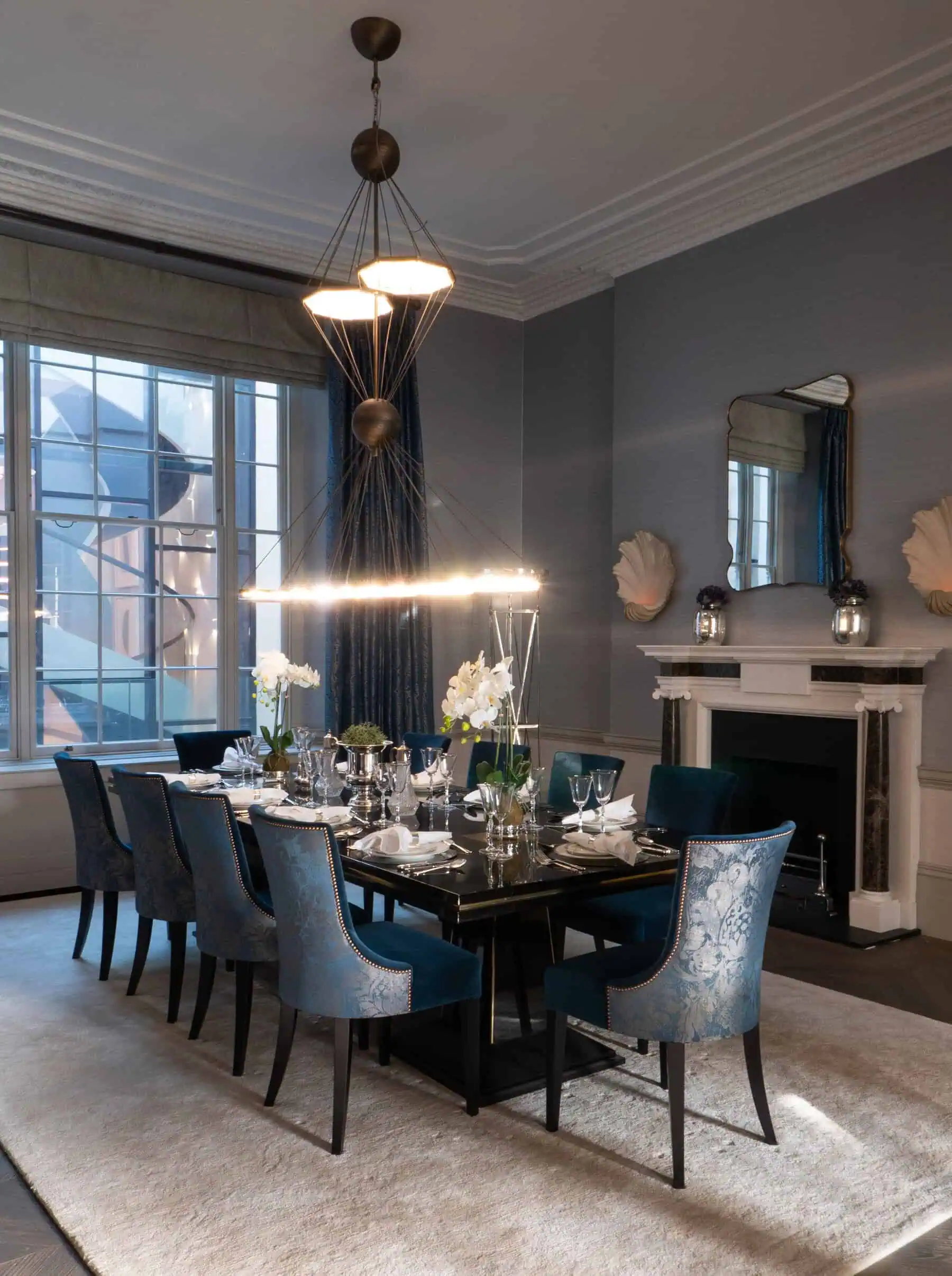 Luxury dining room with tall windows, chandeliers, and upholstered seating.