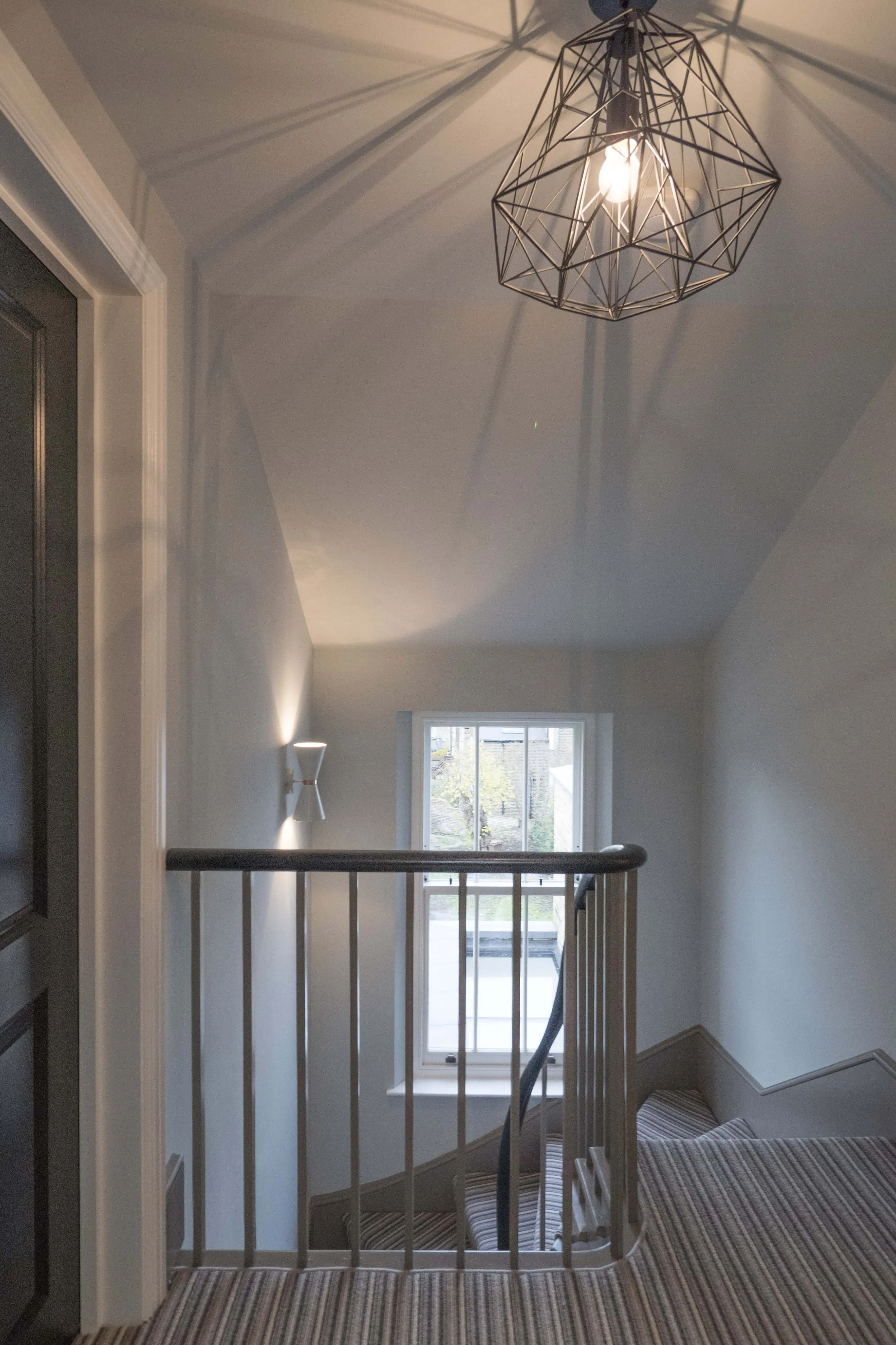 Landing with staircase and geometric pendant light in a Hackney modern extension